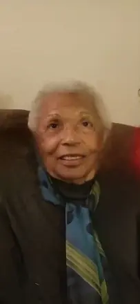 Elderly person sitting and smiling.