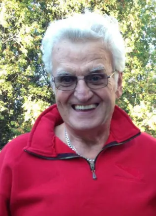 Smiling man in red jacket outdoors.
