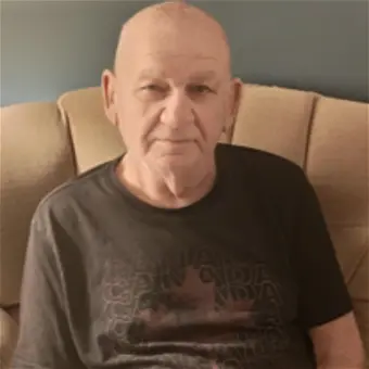 Elderly man sitting on a beige couch.