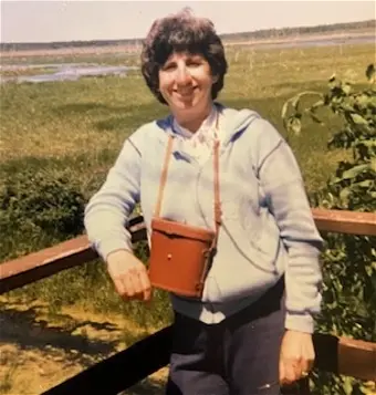 Woman smiling in outdoor nature setting on deck.