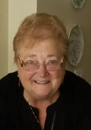 Smiling elderly woman wearing glasses indoors.