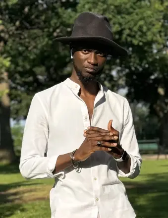 Man in hat and white shirt outdoors.