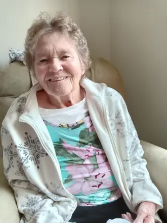 Smiling older woman sitting on a chair.