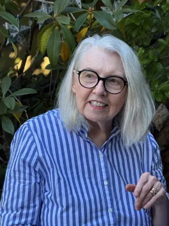 Smiling woman in striped shirt, outdoor setting.