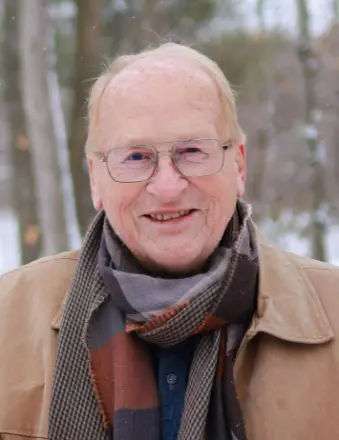 Elderly man outdoors in winter attire smiling.