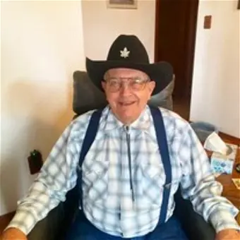 Smiling man in cowboy hat and plaid shirt.