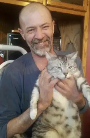 Man happily holding a gray tabby cat
