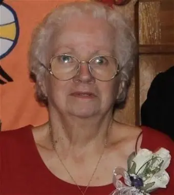 Elderly woman in glasses with floral corsage.