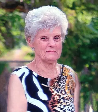Elderly woman in animal print dress outdoors.