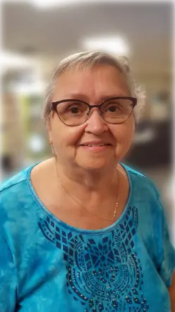 Smiling person in blue shirt wearing glasses.