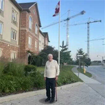 Person standing near Canadian flag, construction cranes visible.