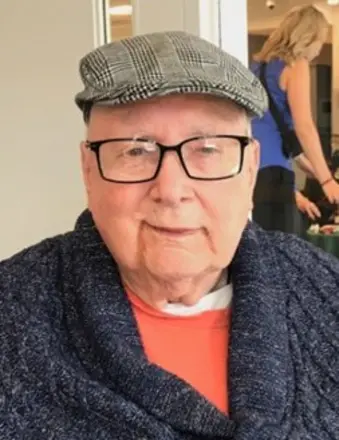 Smiling elderly man wearing glasses and a flat cap.