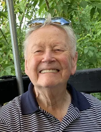 Smiling man in striped shirt outdoors.