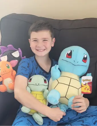 Child holding Pokémon plush toys on couch