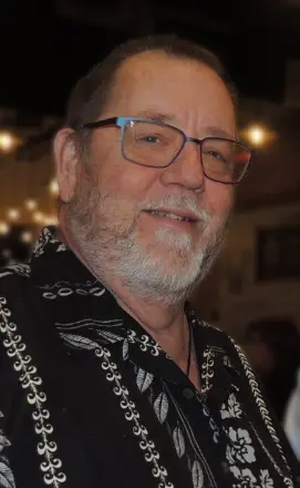 Smiling person wearing glasses and patterned shirt