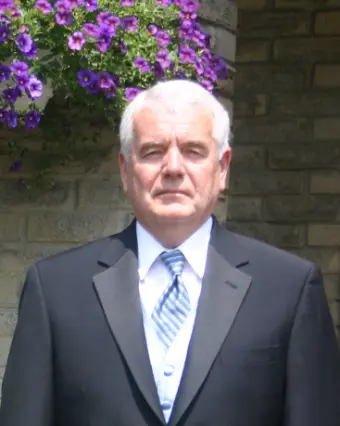 Man in suit standing by purple flowers