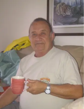 Man holding a red mug, sitting on couch.