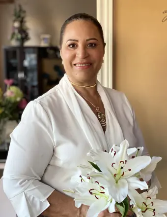 Person holding white lilies indoors.