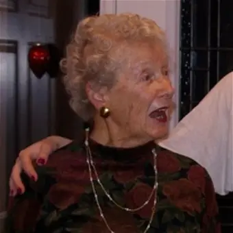 Elderly woman smiling and socializing indoors.