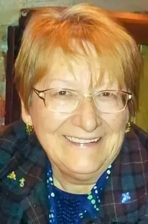 Smiling woman with glasses and short hair indoors.