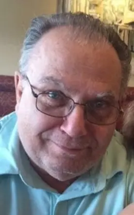 Smiling elderly man with glasses indoors.
