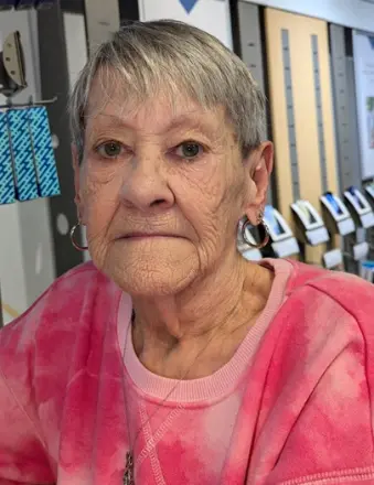 Elderly woman in pink sweater indoors.