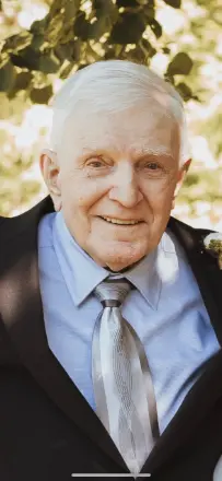 Elderly man smiling in a suit and tie.