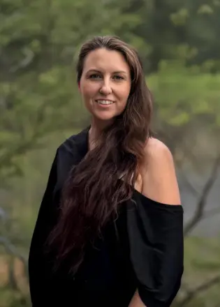 Smiling woman in nature background, wearing black top.