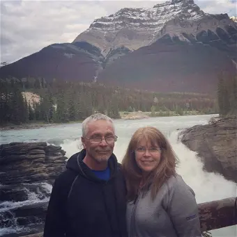 Couple smiling by scenic waterfall and mountains