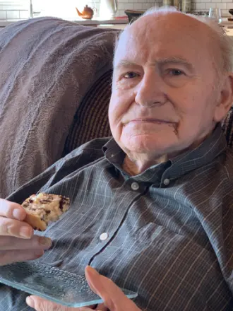 Man enjoying a chocolate chip cookie at home.