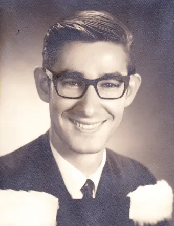 Young man in graduation attire, black and white photo.