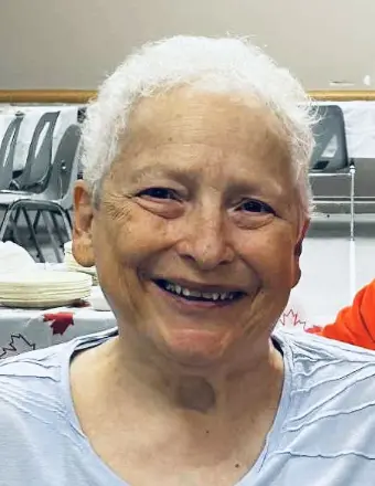 Smiling elderly person sitting at a table indoors.