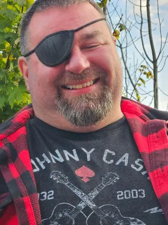 Smiling man with eyepatch and Johnny Cash shirt.