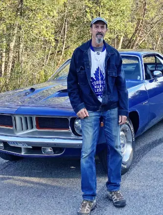 Man standing next to vintage blue car