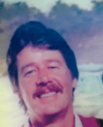 Smiling man outdoors with mustache.