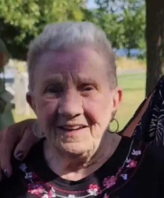 Smiling elderly woman outdoors under trees
