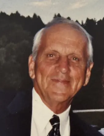 Elderly person in a suit smiling outdoors.