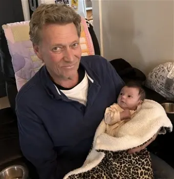 EDWARDS, Wayne Harold Edwards Smiling man holding a baby indoors.