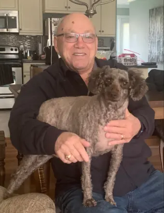 Smiling man holding small dog in kitchen