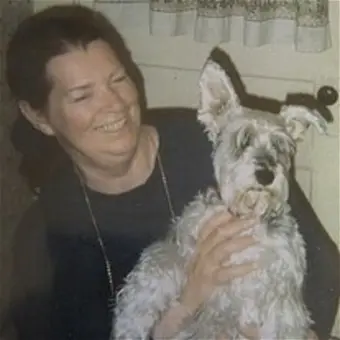 Smiling woman holding a small fluffy dog.
