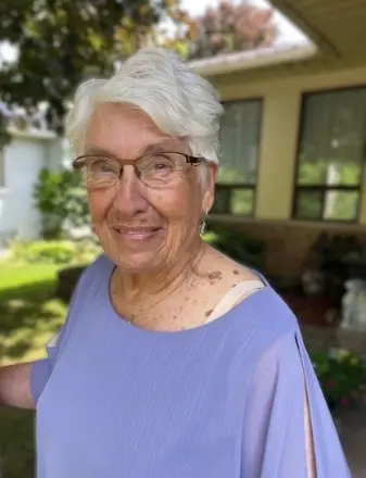 Smiling elderly woman outside her home.