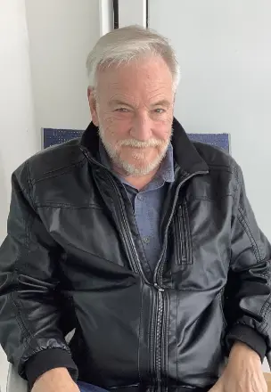 Smiling man in leather jacket sitting indoors