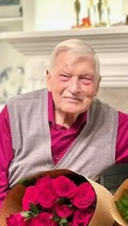Elderly man smiling with bouquet of red roses.