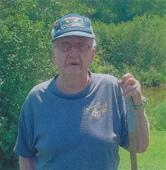 Elderly person outdoors with greenery background.
