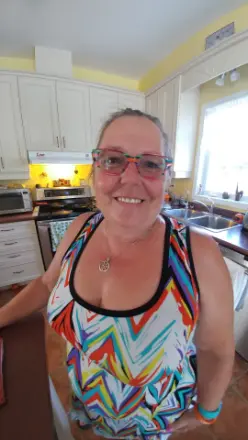 Smiling woman in colorful top, standing in kitchen.