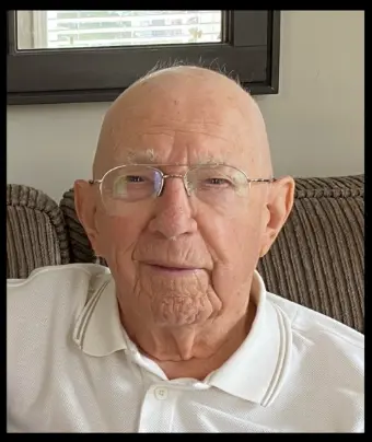 Elderly man in glasses sitting on sofa.