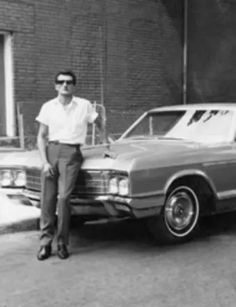Man leaning on vintage car in black and white
