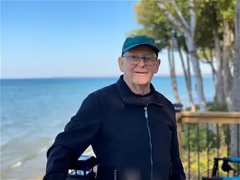 Elderly man smiling by the ocean on a sunny day.