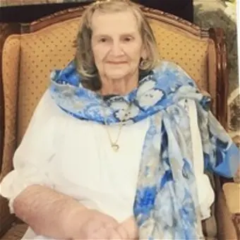 Elderly woman sitting in a chair with scarf.