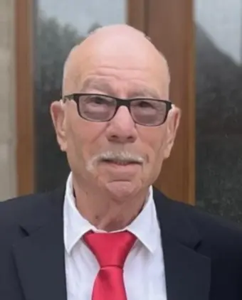 Elderly man in suit and glasses with red tie.